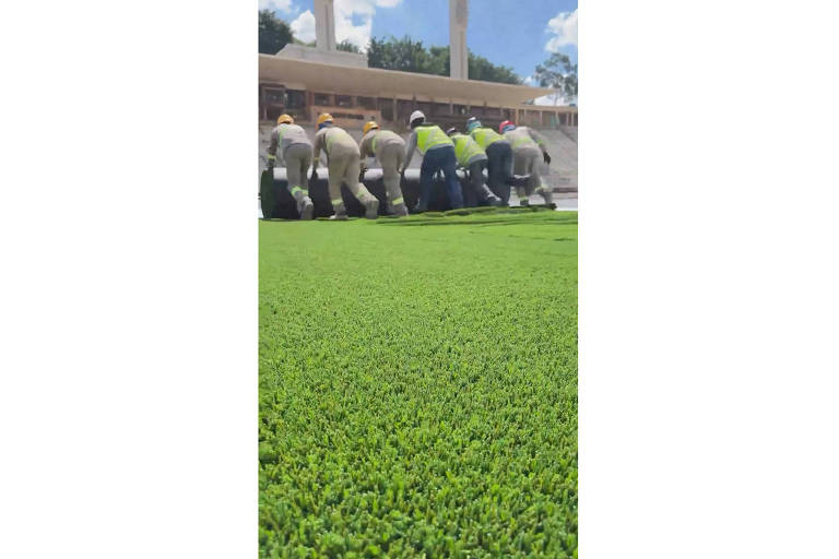 Funcionários instalam novo gramado sintético no estádio do Pacaembu, em São Paulo