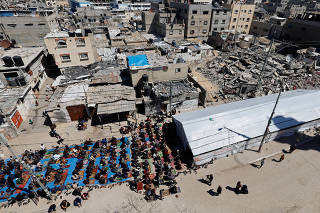 Palestinians perform first Friday prayers during Ramadan near the ruins of a destroyed mosquein, in Rafah