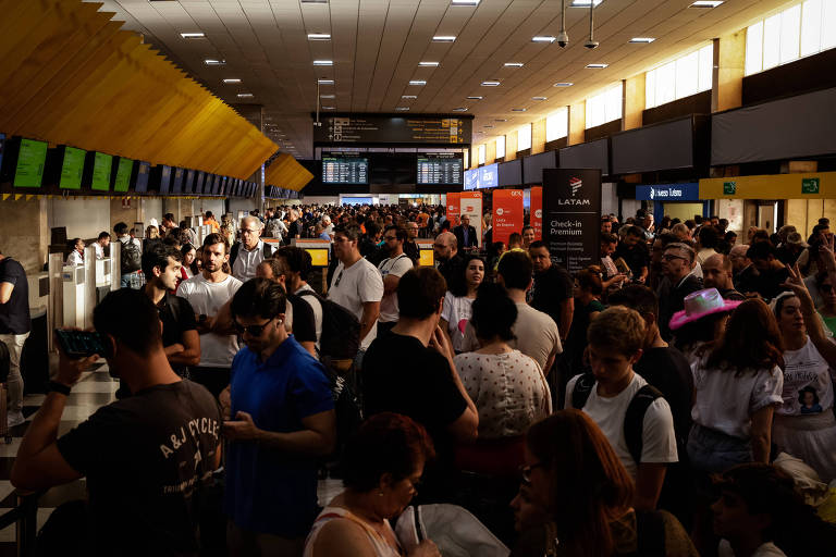 Imagem mostra multidão em saguão de aeroporto.