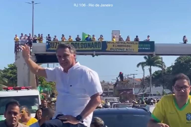 Ex-presidente com camisa branca em cima de um carro acena para apoiadores