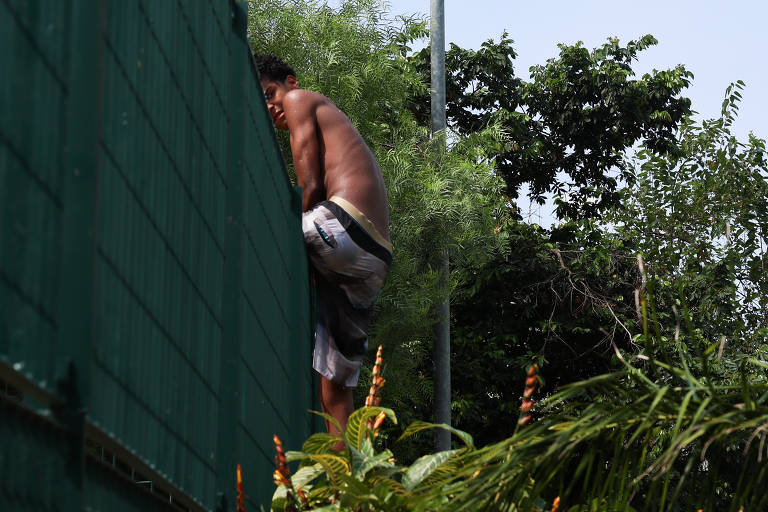Homem sem camisa pula o muro do CEU Butantã, no bairro Jardim Esmeralda, na zona oeste de São Paulo; moradores (muitas crianças e adolescentes) sem carteirinha invadem a piscina do local para se refrescar do calor deste sábado (16)