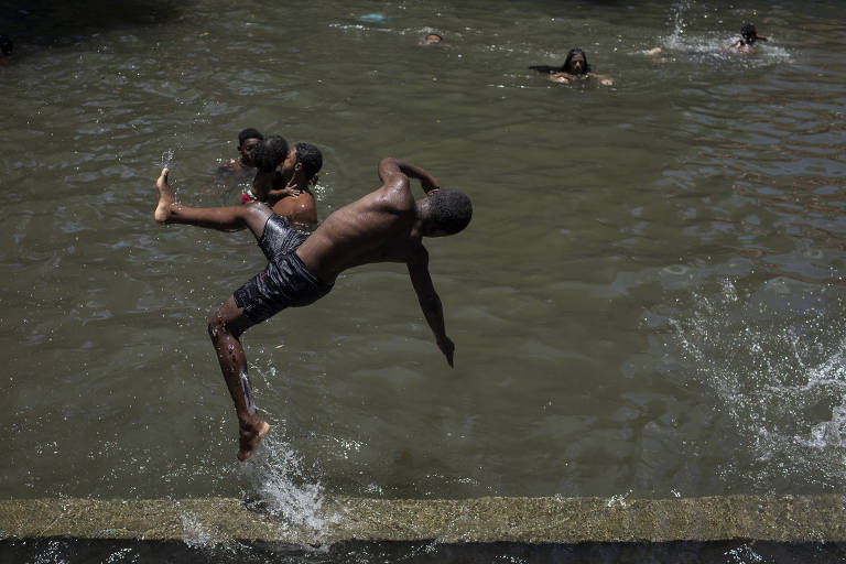 Um garoto negro pula em um tanque de água com o corpo em posição lateral