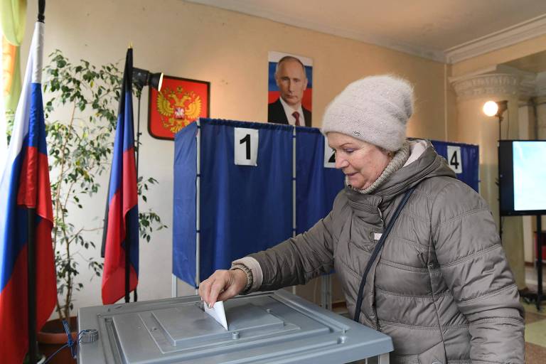 Sob um retrato oficial de Putin, mulher vota em Donetsk, cidade controlada pela Rússia no leste ucraniano