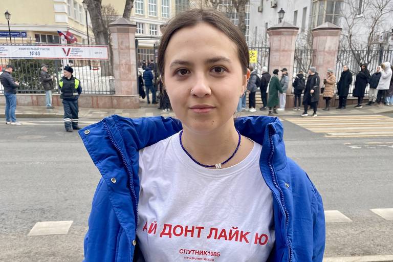 A aluna de moda Marina mostra a camisa com a frase "Eu não gosto de você", usada por críticos de Putin, em frente a fila de votação no centro de Moscou