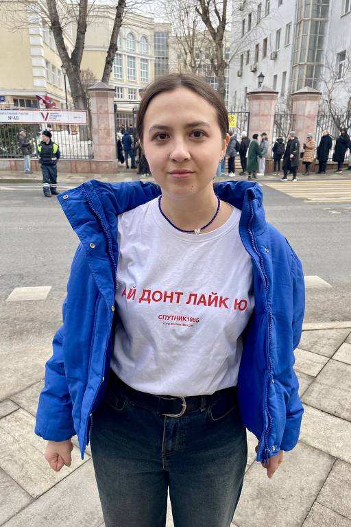 A aluna de moda Marina mostra a camisa com a frase 'Eu não gosto de você', usada por críticos de Putin, em frente a fila de votação no centro de Moscou