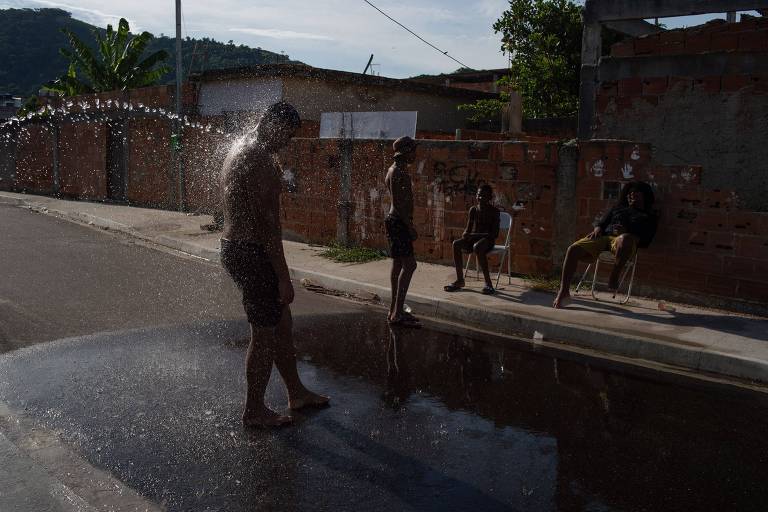 Moradores de Guaratiba se refrescam do calor sufocante tomando banho de mangueira na rua
