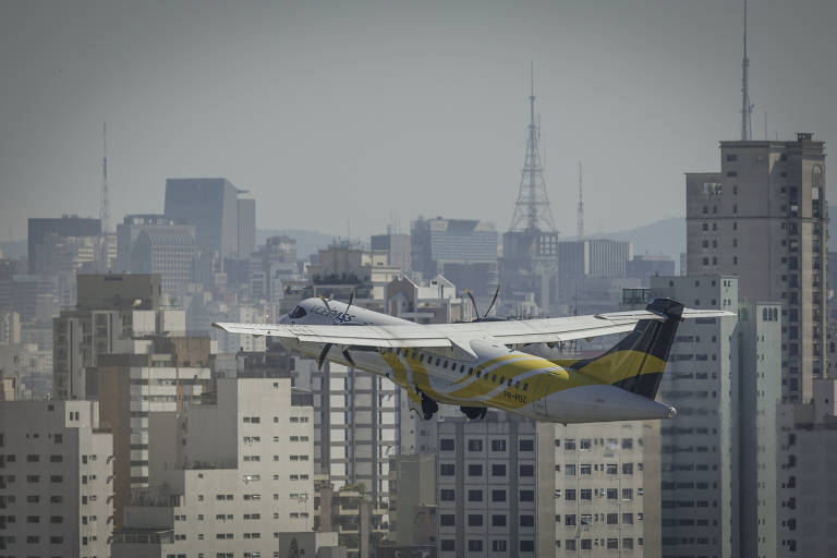 Imagem mostra avião decolando de aeroporto em meio a vários prédios.