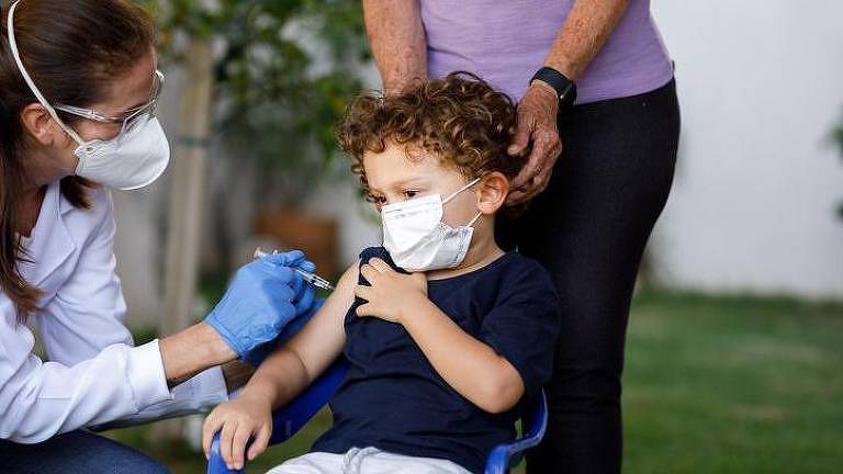 Criança com máscara recebendo vacina