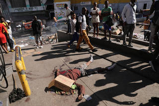 People react at a crime scene, in Port-au-Prince