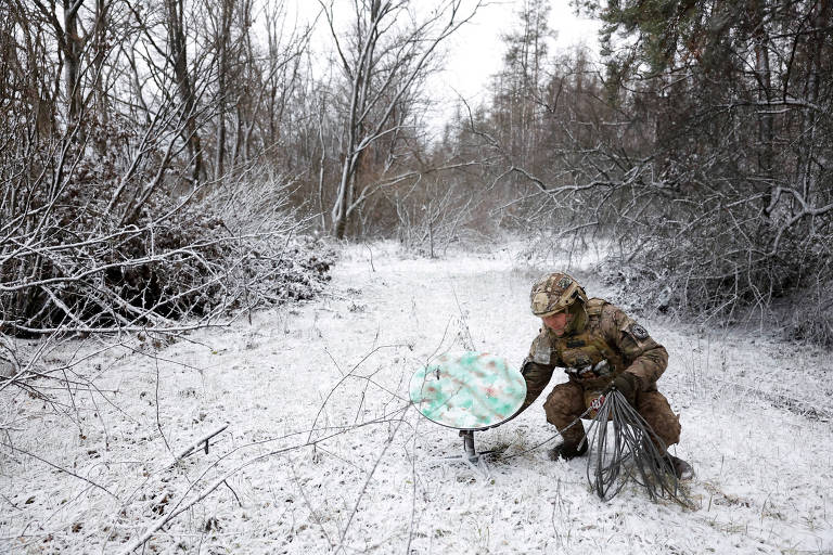 Soldado ucraniano desconecta uma antena do sistema Starlink na região de Kreminna