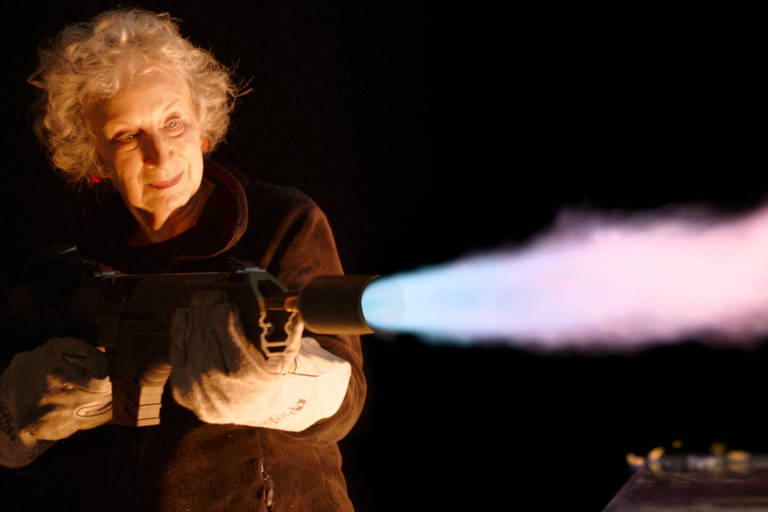 mulher idosa segura lança-chamas ligado enquanto veste equipamentos de proteção