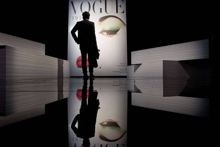 Um homem em frente a uma exposição durante um evento comemorativo do 120º aniversário da revista Vogue