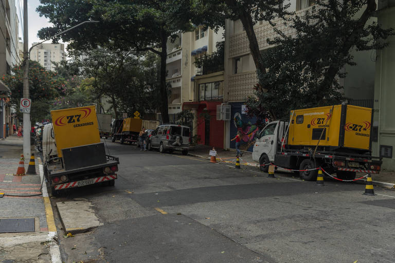Dois caminhões com geradores estacionados, um de cada lado, em via