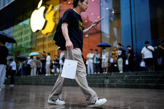 FILE PHOTO: Man carrying Apple's iPhone 15 in a bag in Shanghai, China