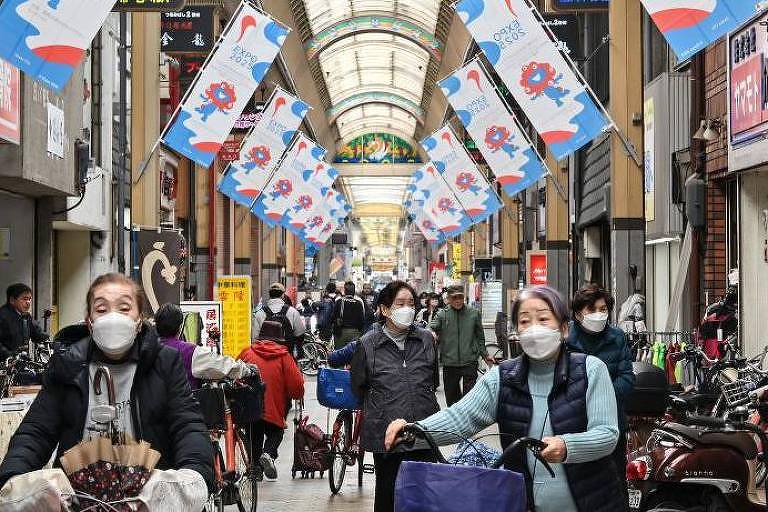 Mulheres com máscaras empurram suas bicicletas nas ruas do Japão