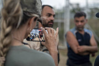 Ann Vandersteel, a podcaster in Florida who has traveled with Michael Yon, records an interview with Yazdan Faramehr, an Iranian migrant, at the San Vicente Migrant Reception Center, Panama, on Feb. 17, 2024. (Federico Rios/The New York Times)