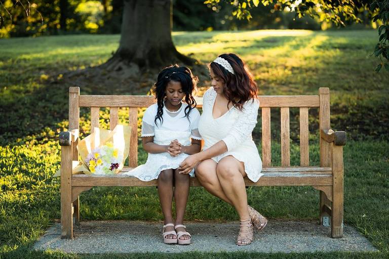 Mãe e filha adolescente sentadas em um banco de praça