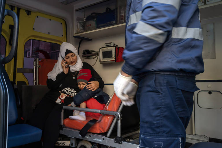 Criança é amparada por mulher coberta por véo dentro de uma ambulância