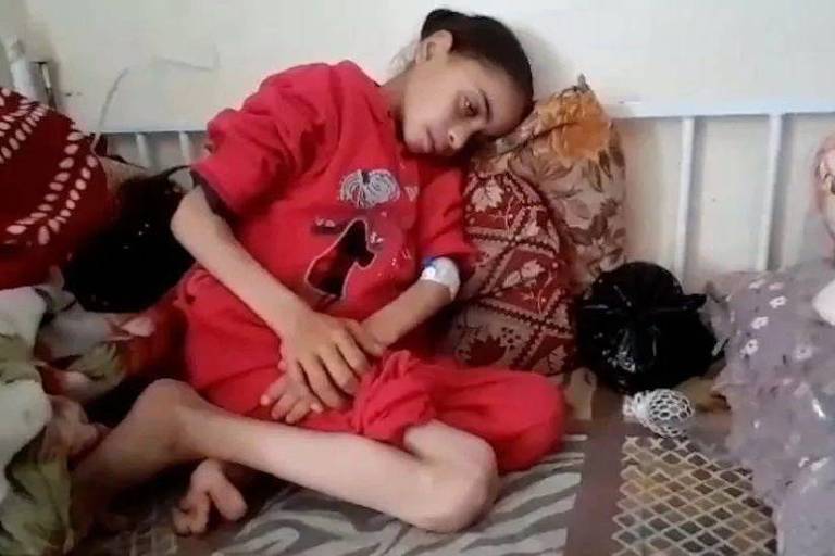 Noora Mohammed sentada encolhida em sofá
