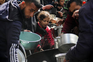Palestinians gather to receive free food in Jabalia in the northern Gaza Strip