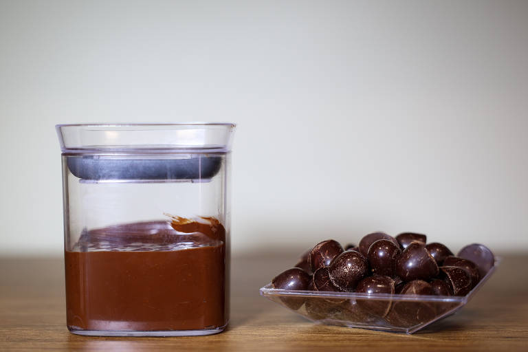 Imagem mostra a produção de chocolate em Jaru (RO). Há uma embalagem transparente com chocolate dentro e, ao lado, chocolate em formato de drágeas.