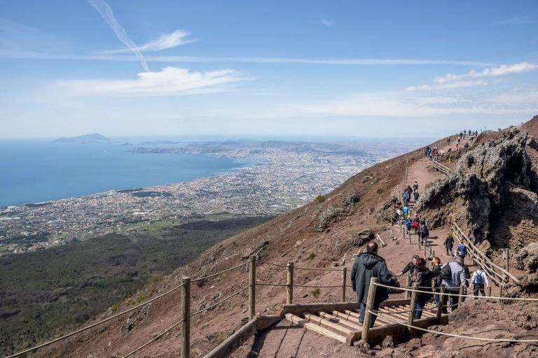 Turistas subindo pela trilha no Monte Vesúvio com vista para Nápoles