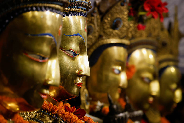 Estátuas budistas exibidas para fiéis do Nepal durante festival religioso. As figuras do Buda são douradas com cabelos pretos e expressão facial serena 