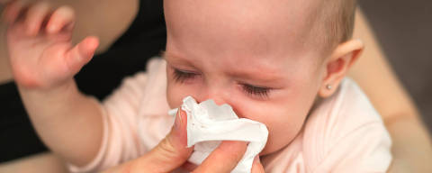 A small, sick, crying child, whom the mother wipes with a paper towel - (Photo: ondrooo/Adobe Stock) DIREITOS RESERVADOS. NÃO PUBLICAR SEM AUTORIZAÇÃO DO DETENTOR DOS DIREITOS AUTORAIS E DE IMAGEM