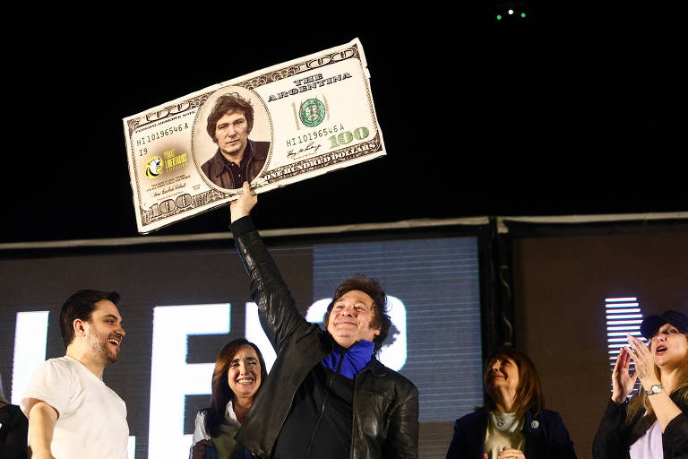 Presidente argentino Javier Milei segura uma placa simulando uma nota de US$ 100 estilizada com seu rosto