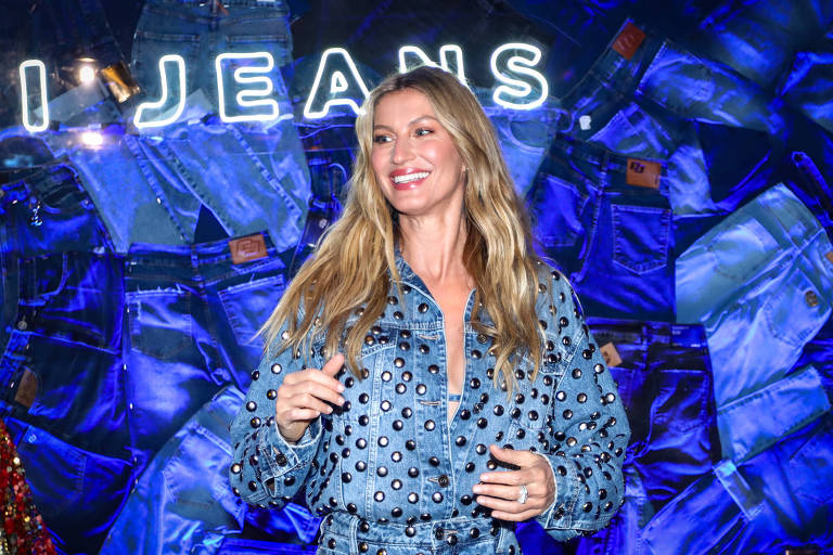 Em foto colorida, mulher vestida de calça e jaqueta jeans posa para foto