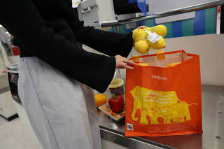 A customer puts groceries inside a reusable bag at the self-checkout inside a Sainsbury?s supermarket in London