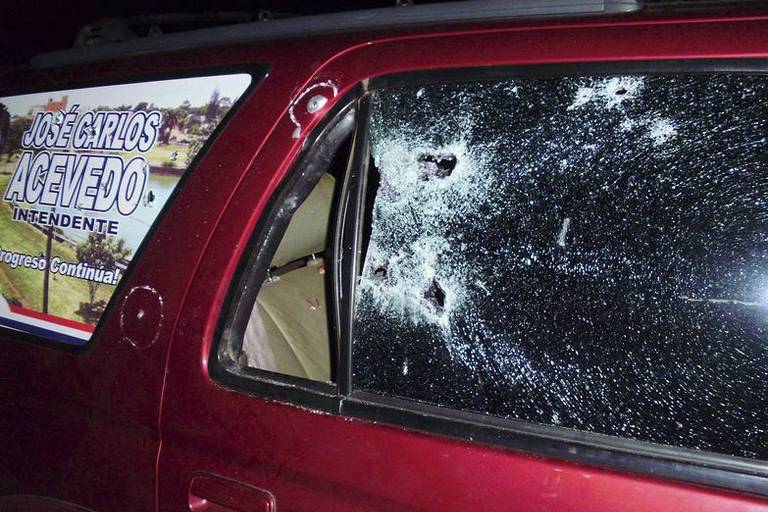 caminhonete com buracos no vidro e estilhados causados por disparo de arma de fogo. 