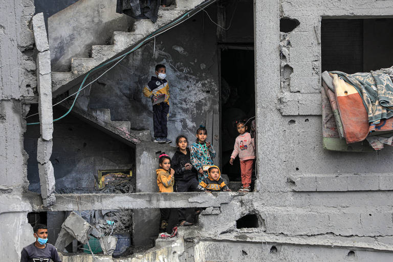 Crianças em meio a prédio destruído na cidade de Rafah, no sul da Faixa de Gaza, em fevereiro