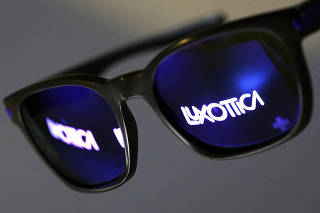 FILE PHOTO: The Luxottica name is reflected in a pair of sunglasses  in this photo illustration taken in Rome
