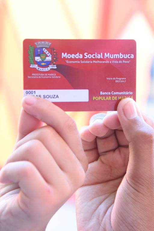 Imagem mostra cartão vermelho escrito moeda social mumbuca