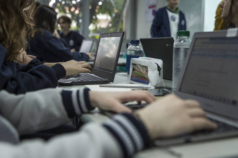 Imagem mostra menina digitando em computador na sala de aula