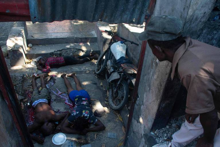 Homem observa corpos de pessoas mortas em rua de Porto Príncipe, a capital do Haiti