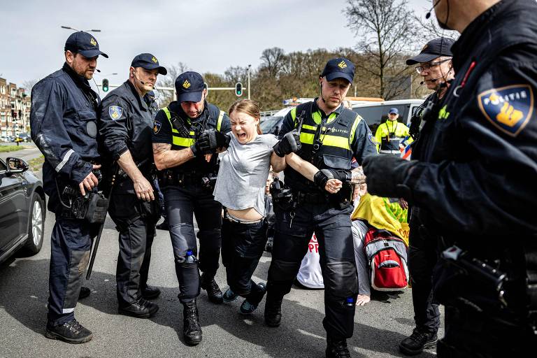 A ativista climática sueca Greta Thunberg grita ao ser presa e arrastada por dois policiais durante uma marcha climática contra os subsídios fósseis perto da rodovia A12 em Haia.