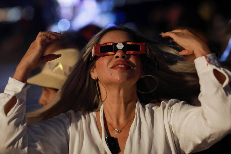 Mulher usa óculos especiais para observar o eclipse solar no México
