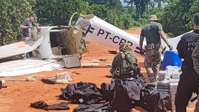 Agentes da Polícia Federal e da FAB juntam os pacotes de drogas que estavam no avião que fez aterrissagem forçada nesta terça-feira (9), nas proximidades de Londrina (PR)