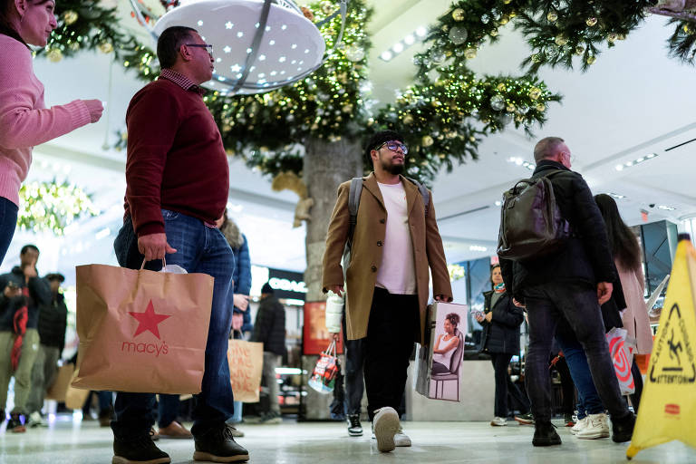 Pessoas entram na loja principal da Macy's enquanto carregam suas sacolas de compras durante a temporada de férias na cidade de Nova York, EUA
