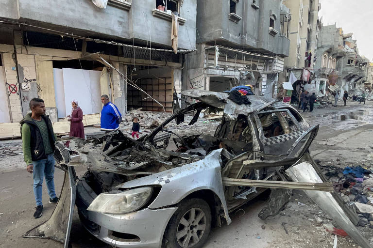 Palestinos próximos de destroços de carro que transportava familiares de Ismail Haniyeh e foi atingido por drone