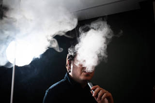 O jornalista Alexandro Lucian fumando cigarro eletrônico, proibido desde 2009 no país
