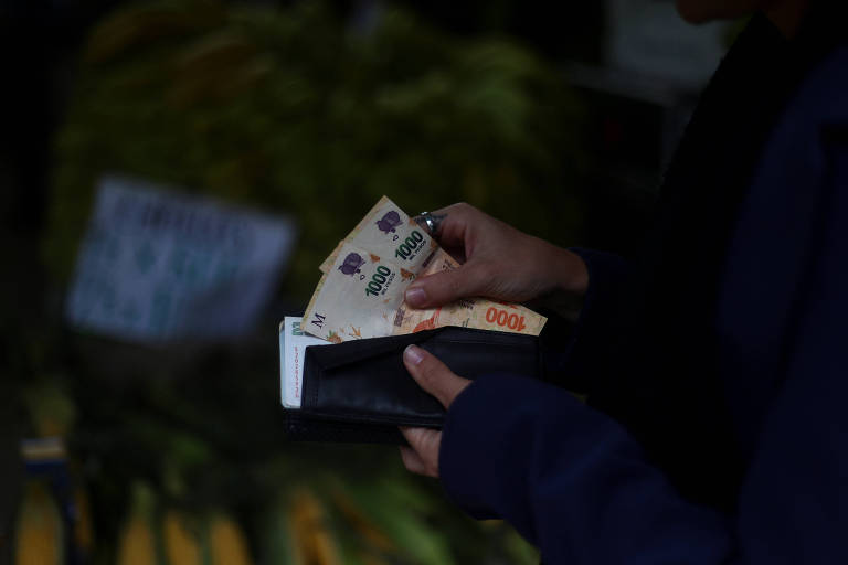 Cliente conta notas de 1.000 pesos (em torno de R$ 5) em um mercado de verduras em Buenos Aires