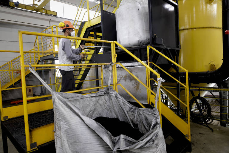 Funcionário da usina CBB, em Paulínia (SP), coloca pó de pneus em moinho para a fabricação do ligante asfáltico, que depois será misturado ao cimento asfáltico para aplicar nas rodovias