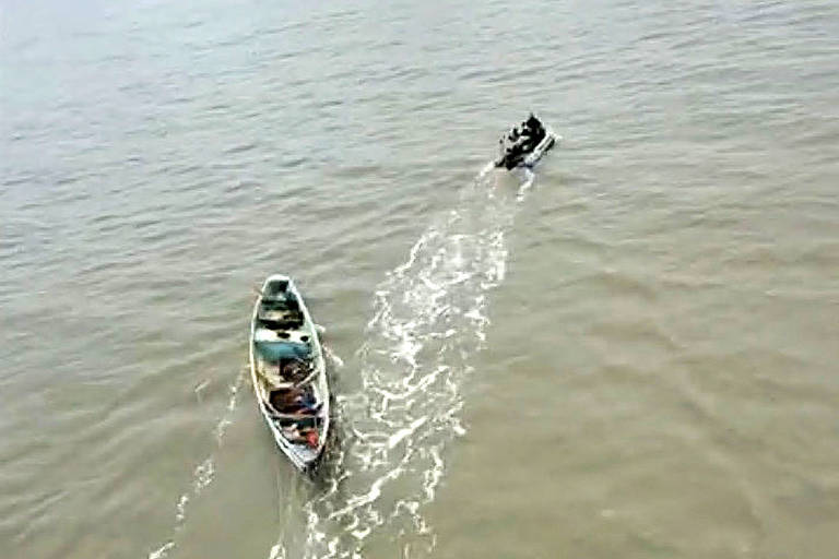 Vista aérea de um barco com roupas e uma lancha da Polícia Federal 