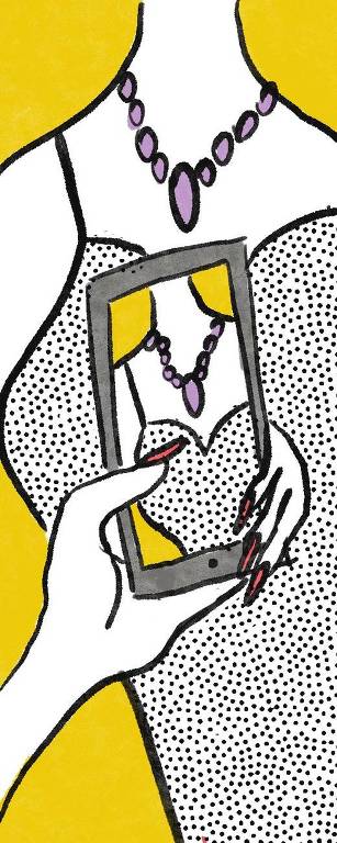 Mão de uma mulher segurando o celular tirando foto de outra mulher cuja imagem, focando no colar,  aparece na tela do telefone.