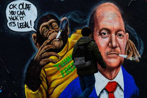 A man walks past a mural by Berlin-based graffiti artist Eme Freethinker depicting a chimpanzee handing a joint to a likeness of German Chancellor Olaf Scholz in Berlin on April 1, 2024, as a law allowing adults to carry up to 25 grams of dried cannabis and grow up to three marijuana plants at home came into effect in Germany. (Photo by John MACDOUGALL / AFP) / RESTRICTED TO EDITORIAL USE - MANDATORY MENTION OF THE ARTIST UPON PUBLICATION - TO ILLUSTRATE THE EVENT AS SPECIFIED IN THE CAPTION