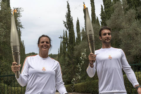 (240416) -- ANCIENT OLYMPIA, April 16, 2024 (Xinhua) -- The first torch bearer, Greek rowing Olympic champion Stefanos Ntouskos (R) and the second torch bearer, French swimming Olympic champion Laure Manaudou pose during the torch relay after the Olympic flame lighting ceremony for the Paris 2024 Summer Olympic Games in Ancient Olympia, Greece, on April 16, 2024. (Xinhua/Marios Lolos)