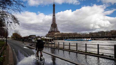 A person rides a bike on the flooded Seine river banks with the Eiffel Tower appearing in the background in Paris on March 5, 2024. (Photo by Guillaume BAPTISTE / AFP)